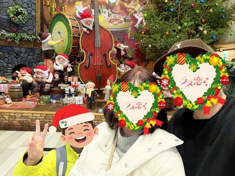 クリスマスをテーマにした華やかなディスプレイの前でポーズをとる家族の写真です。