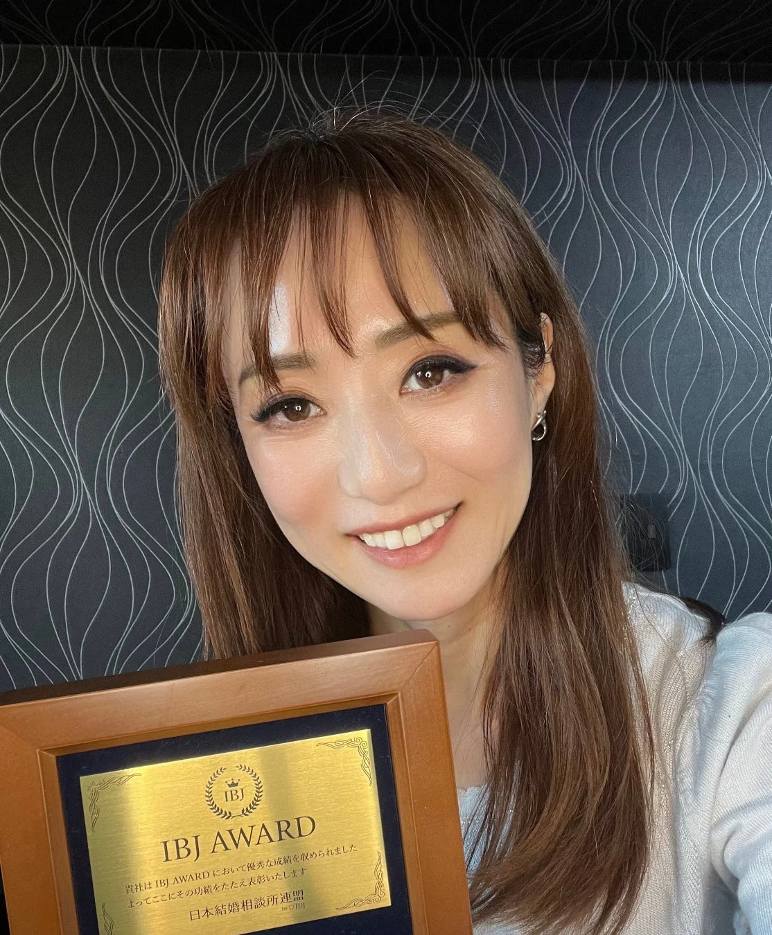 IBJ AWARDの表彰状を手に満面の笑みを浮かべる女性