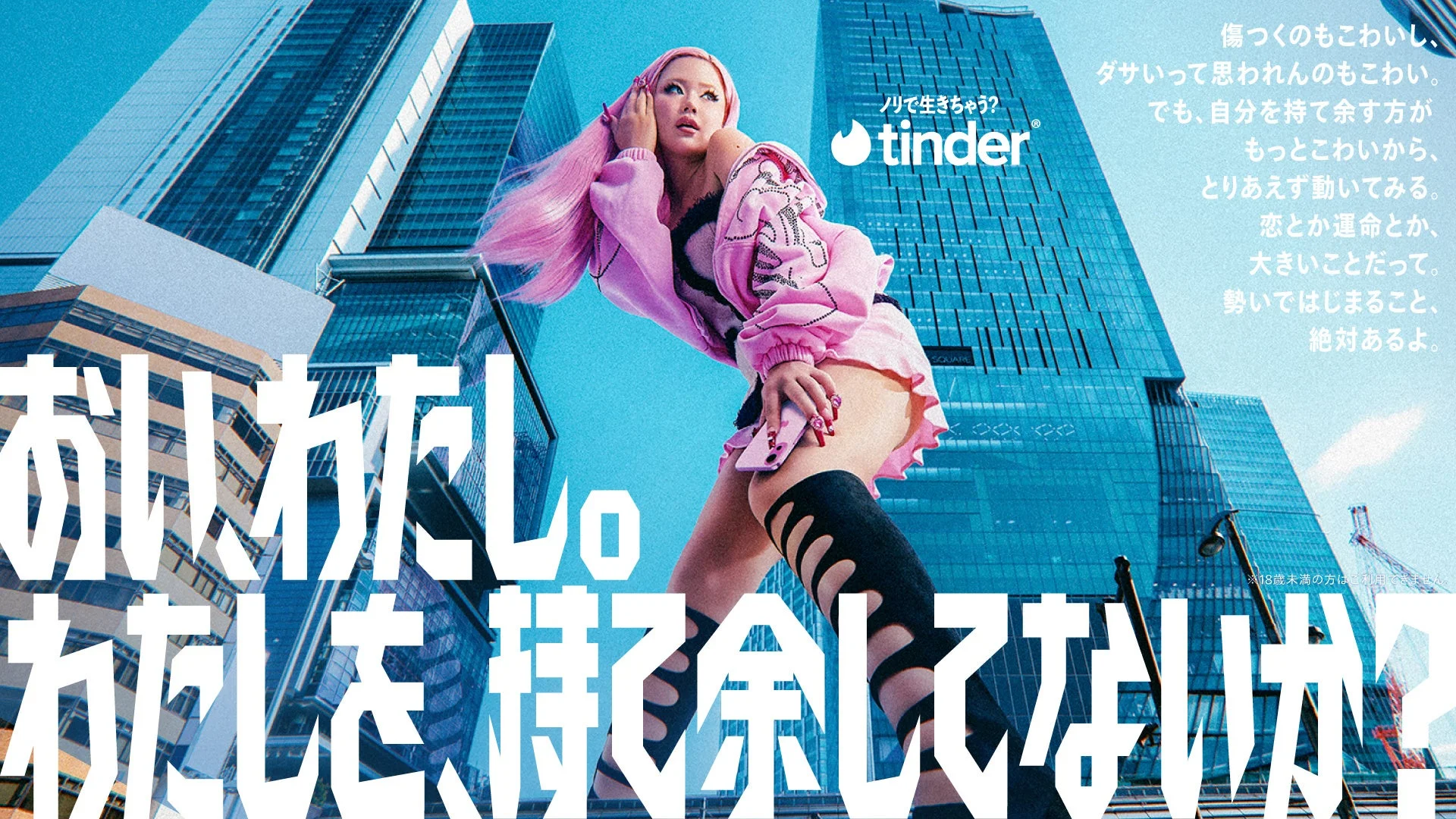 ピンク髪の女性が高層ビルを背景にポーズをとるTinder広告。自分を持て余すことへの恐れを強調し、行動することの重要性を訴える。若者向けのポップで都会的な雰囲気。