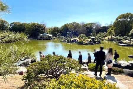 日本庭園の池の畔に集まる人々