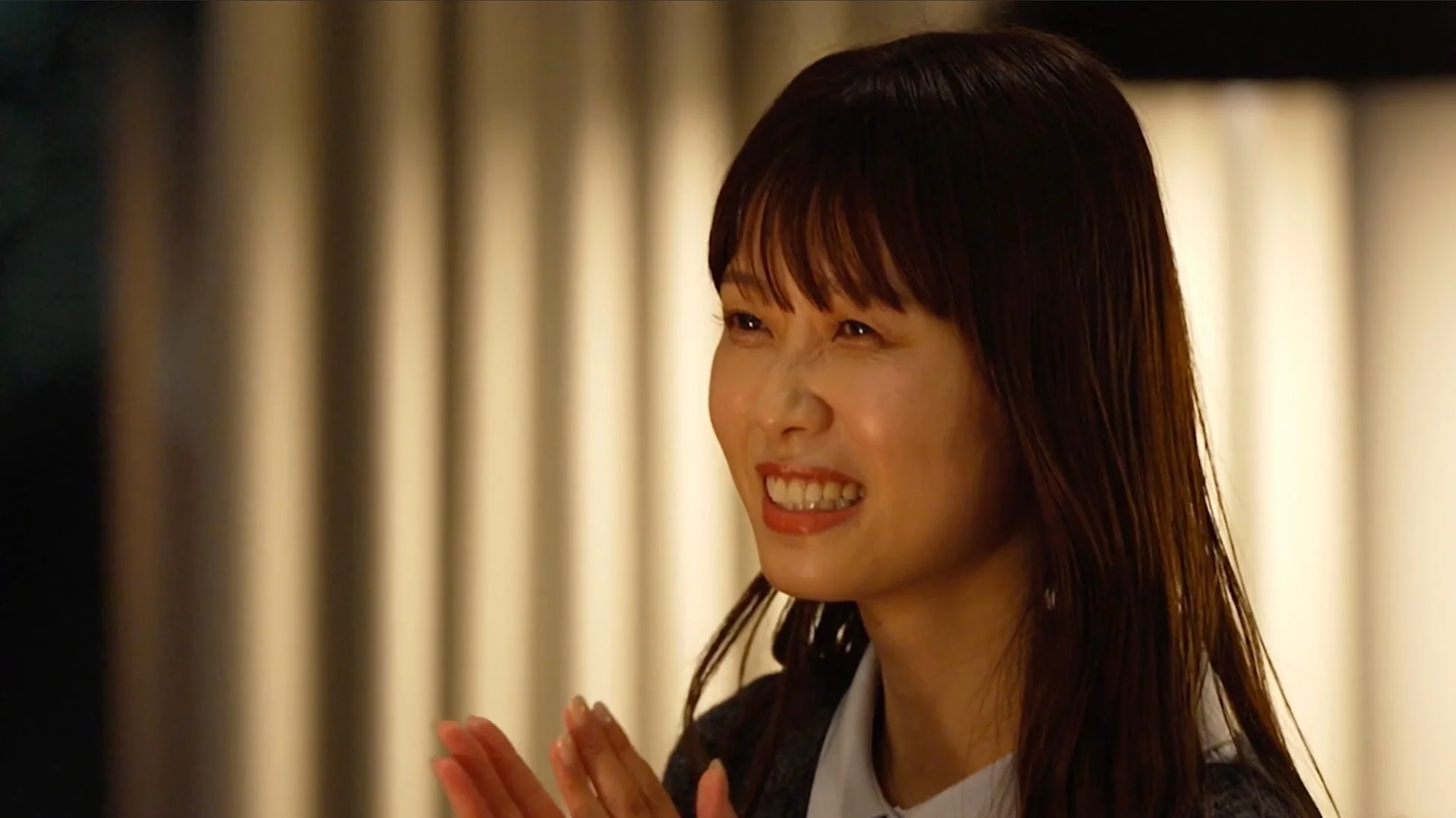 満面の笑みを浮かべ、手を叩いている若い女性のポートレート。